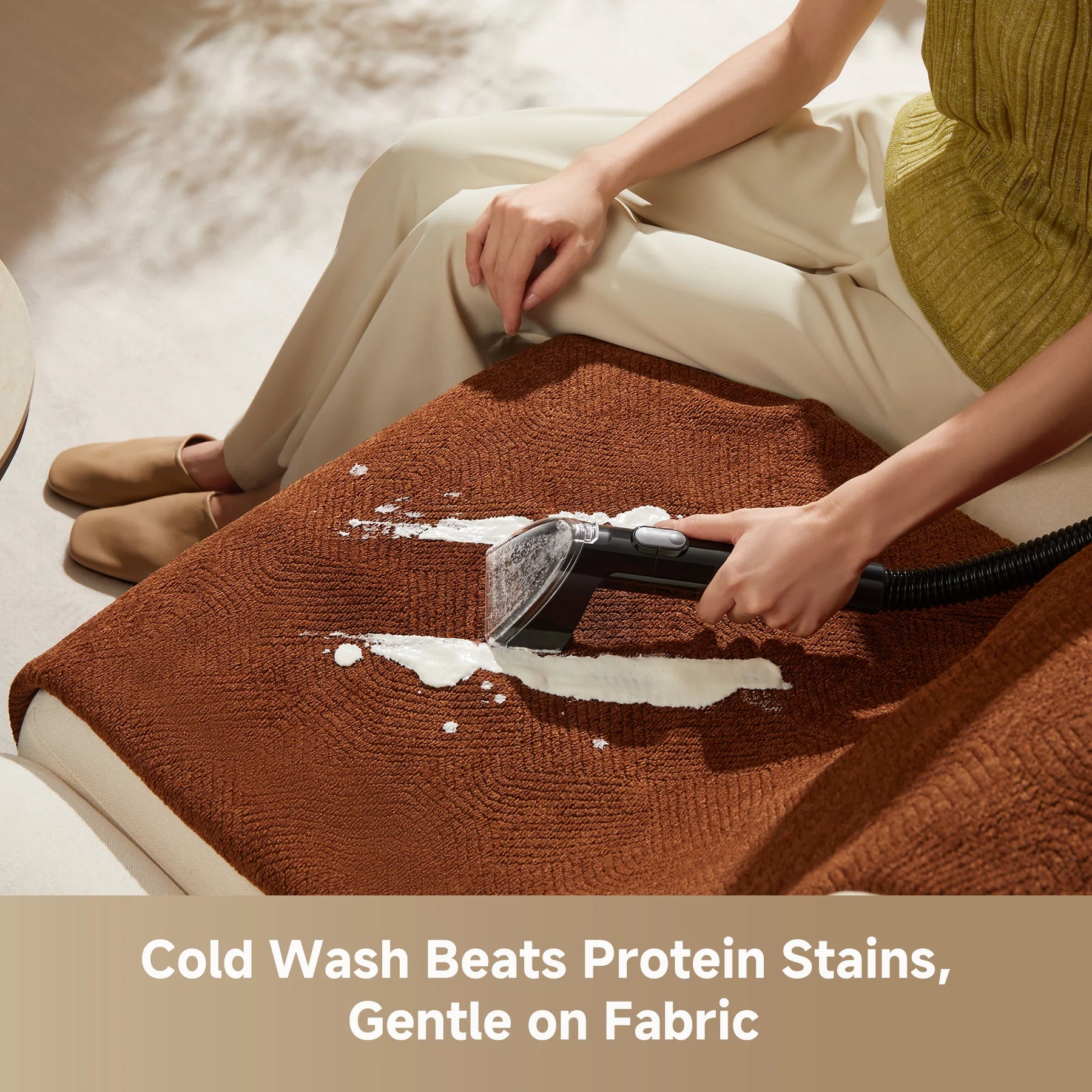 Steam spot cleaner wand cleaning a brown fabric cushion surface